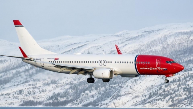 image of  Norwegian airlines flying over snowy mountains