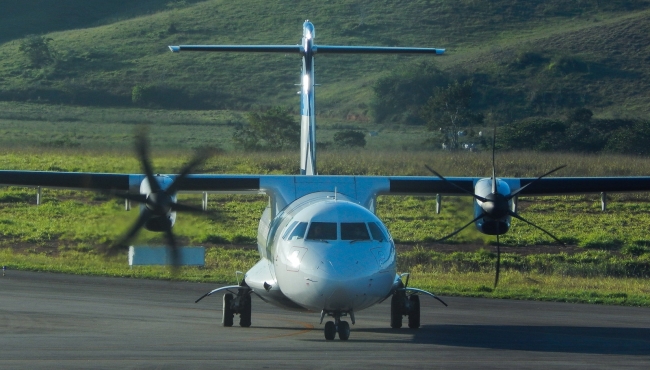 An ATR72-600 aircraft taxiing on the ground with engines running