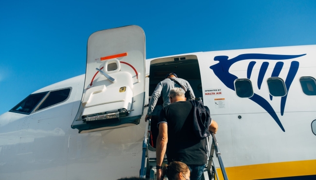 Passengers boarding a Ryanair Boeing 737 aircraft with door open and airstairs extended