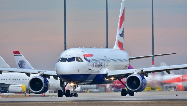 A British Airways Airbus A320 passenger jet airliner on the ground at Gatwick Airport with Norwegian Air and EasyJet aircraft parked in the background