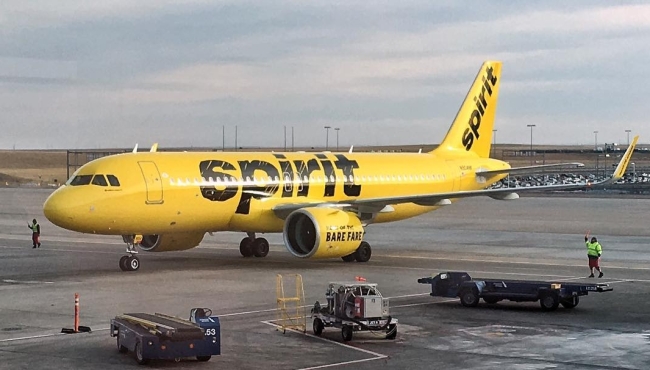 An image showing a yellow Spirit Airlines Airbus A320neo aircraft on the ground at an airport