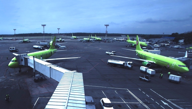 A group of Russian S7 airlines Airbus A320 jet airliner aircraft with airbridge steps attached at an airport