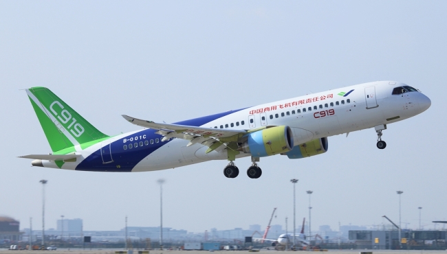 A Comac C919 passenger jet aircraft on takeoff with sky and buildings in the background