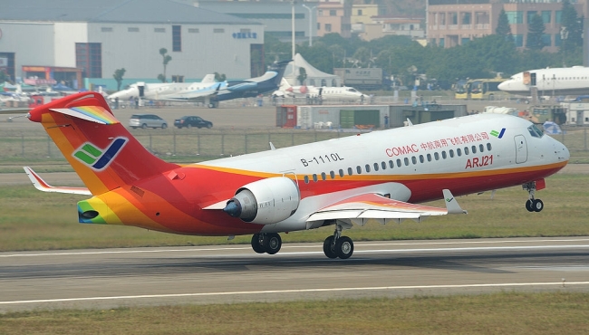 An orange, red and white COMAC ARJ21 aircraft lifting off from a runway