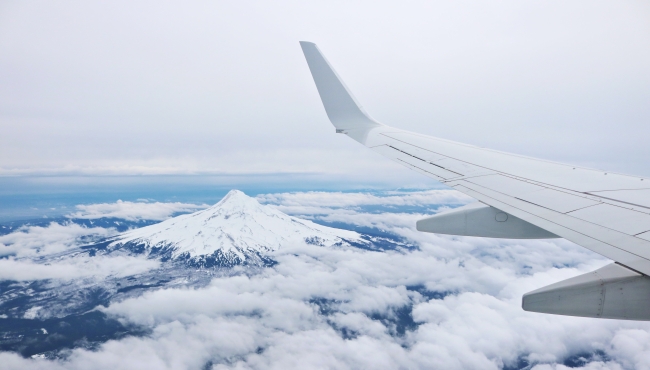 Image of an aeroplane wing with a mountain in the background