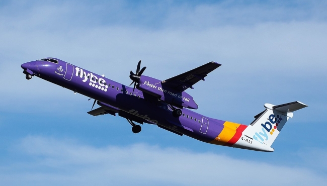 a flybe dash 8 prop aircraft taking off in a blue sky