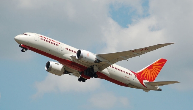 a white and orange air india 787 passenger jet aircraft taking off with blue skies