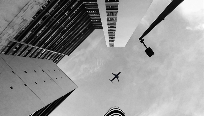 image of a plane flying over buildings
