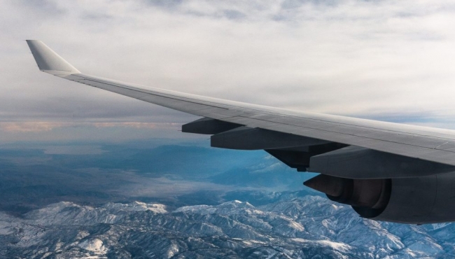 image of an aeroplane wing flying over mountains