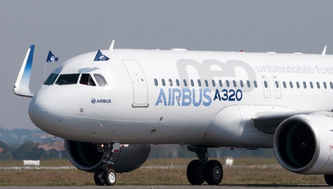 An Airbus A320 neo aircraft jet on the ground at an airport with open windows and flags in the cockpit
