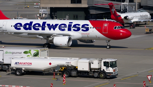A jet airliner aircraft being refuelled at an airport with a fuel truck in the foreground