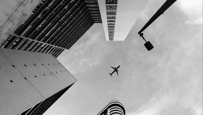 image of an aeroplane flying above buildings
