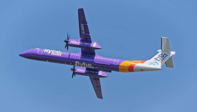 a flybe dash 8 q400 aircraft in flight with blue sky behind