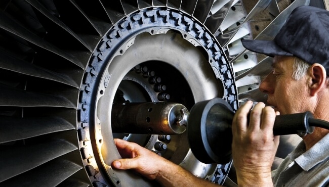 image of a man looking inside an aircraft engine